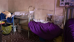 A doctor's office in Sierra Leone is pictured. Older and sparse medical equipment and supplies line the brown walls. Ventilation Corner is written on the wall in black.