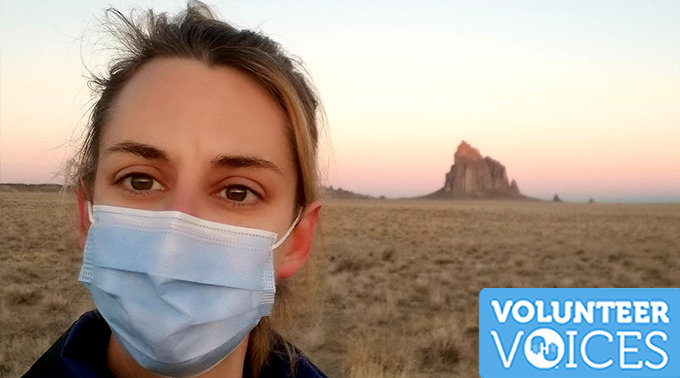 Project HOPE volunteer Lisa Bartleson takes a photo of herself with her medical mask on against a background of a lovely sunset at Shiprock, New Mexico. 