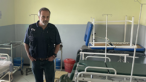 Our CEO Rabih Torbay wears a navy Project HOPE vest, polo and jeans as his hands rest in his pockets in a room of gurneys and IV stands in an Ethiopian health facility.