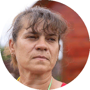 A photograph of a Ukrainian woman's head. She has medium brown hair and bangs in a pony tail and wear earings. She is looking pensively to the right