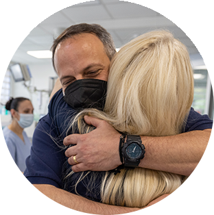 Project HOPE CEO Rabih Torbay smile unders his medical mask as he hugs a Ukrainian team member in a hospital.