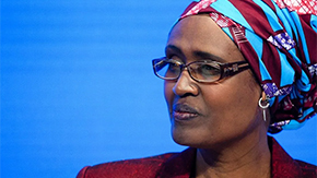 A photograph of Winnie Byanyima looking to the side. She is wearing glasses and a patterned head scarf with earrings and a suit jacket. She is a champion for women’s rights in the Parliament of Uganda. Photo by World Economic Forum and licensed under CC BY-NC-SA 2.0.