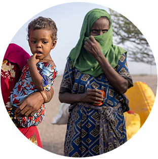 A round photograph of a family in Ethiopia carrying large yellow water containers. There is a woman covering her face with her head scarf and a young child being held by its mother. They all are wearing brightly colored and patterned dresses.