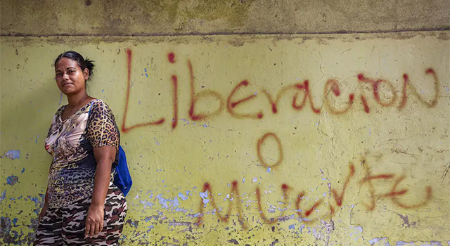 A photograph of a Venezuelan woman who was forced to flee to Colombia and now is a Project HOPE-supported community health worker, connecting pregnant woman with medical services. She wears clothes with prints and a small backpack.