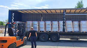 A photograph of an 18-wheeler full of crates of bottled water with two men working to unload them in Ukraine.