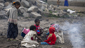 A photograph of a group of children gathered in a circle and playing on the ground outside an IDP camp where Project HOPE provides health care.