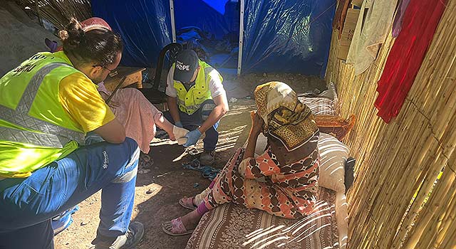 A photograph of Project HOPE's local partners wrapping a woman in a long dress foot after the recent earthquake in Morocco.