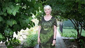 A photograph of an older woman and Ukrainian refugee with short hair at a community center garden in Poland.