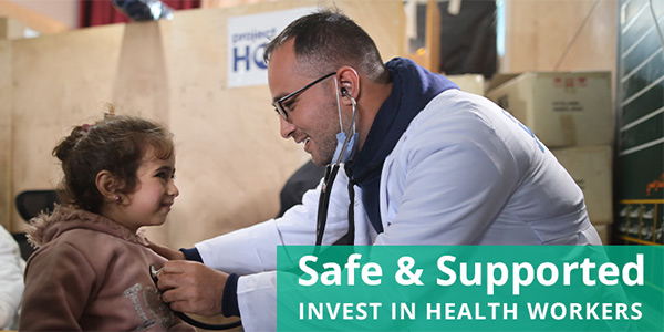 Photograph of a doctor wearing glasses and a lab coat using a stethoscope to listen to a young girl wearing a hoodie and a slight smile's heart in a Project HOPE-supported clinic in Gaza.