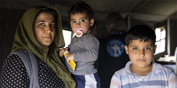 Photograph of a family of three in Turkiye in a medical tent run by Project HOPE partners.