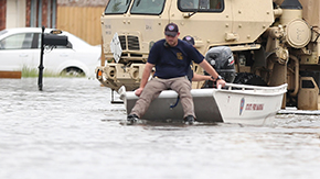 A first responder in Louisiana wears a navy polo and khaki pants with a backpack as he descends from a boat to help people stuck after Hurricane Ida last year.