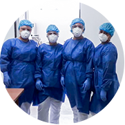 A photograph in the shape of a circle shows four health workers in a Colombian hospital standing side-by-side. They are all wearing a white face mask, blue surgical gloves, coat and head covering as they stand in front of the entrance to a hospital room.