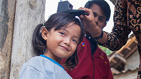 A girl in Indonesia has her height recorded by a volunteer health worker