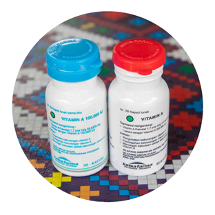 Two round plastic white medicine bottles are sitting on a brightly-patterned table. One has a blue top and the other a red one.