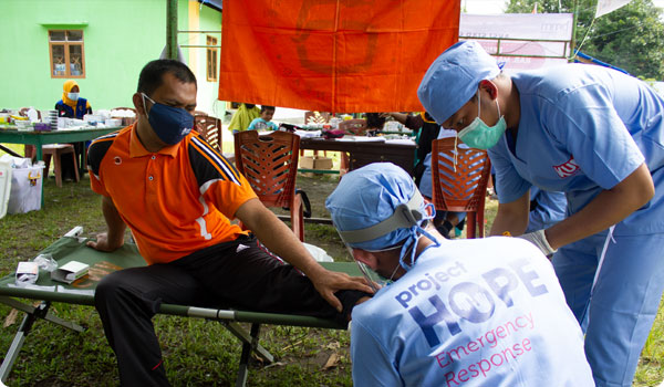 Man having his leg treated by two health care workers.