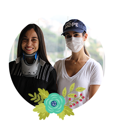 Two women stand together smiling in Beirut. One wears a neck brace after being injured in this summer's explosion.