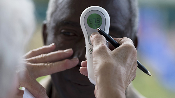 A nurse reads a temperature with an infrared thermometer