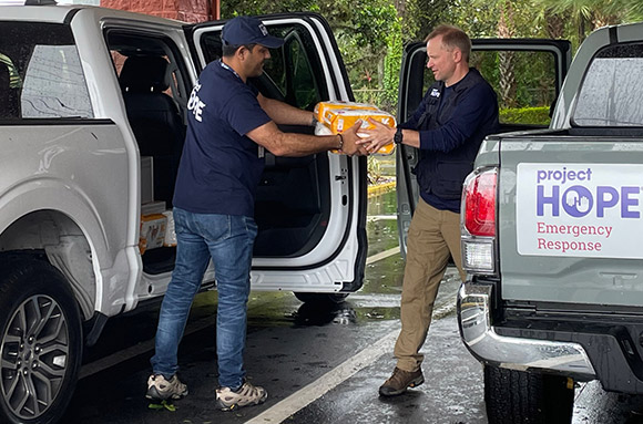 Project HOPE’s Emergency Response Team passes needed supplies between two trucks after a hurricane. 