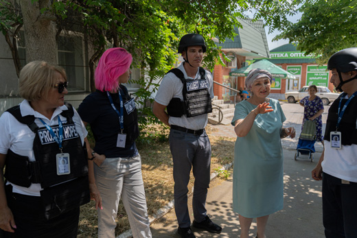 A photo of Chris Skopec speaking with Project HOPE teams in Ukraine. They are wearing bulletproof vests as they talk outside.