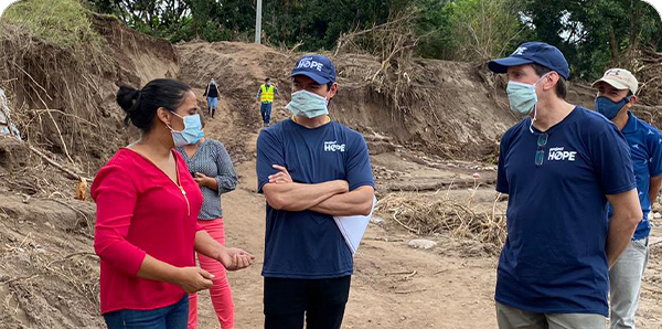 People in Project HOPE uniforms talk to residents impacted by the hurricane in Honduras.