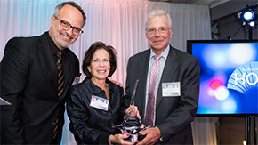 A photograph of Gail smiling as she accepts an award from Project HOPE colleagues.