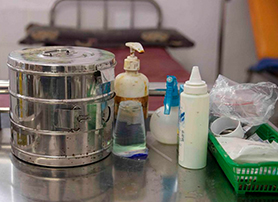 Medical supplies including solutions and gloves sit on a stainless steel medical cart in Indonesia