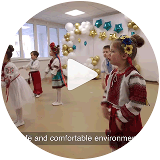 A photograph showing small Ukrainian children performing a dance in traditional costumes in a newly rebuilt kindergarten.