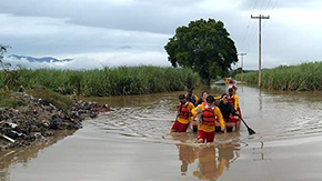 A group of people pushes a boat down the street of a flooded town in Honduras