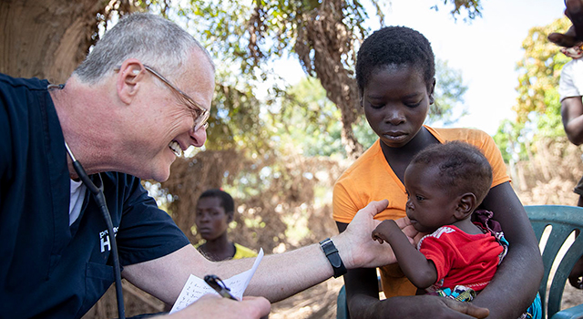 A Project HOPE doctor smiles at a young boy being held by his mother