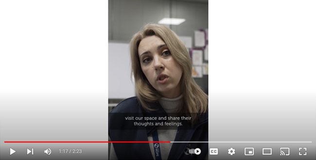 A screenshot of a vertical video shows a Project-Hope supported psychologist in Ukraine as she talks about her work, against the background of a whiteboard and children's art. The caption on the screen reads: visit our space and share their thoughts and feelings. 