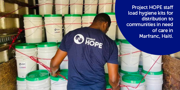 Photograph of a Project HOPE team member in the back of a truck as they examine stacks of buckets containing hygiene kits for distribution to families in Haiti.